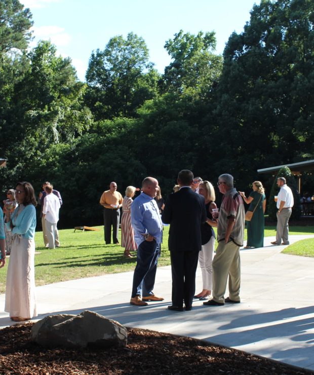 People standing in small groups at an outdoor event.