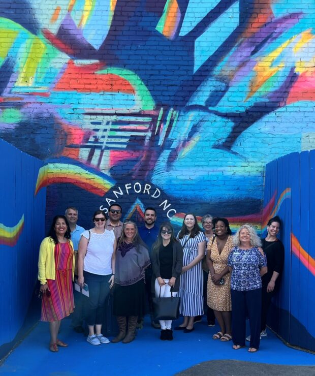 leadership sanford participants standing in front of a rainbow colored mural
