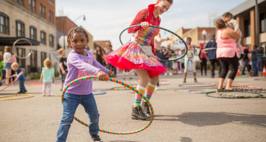 little girl hoola hoops at street fair